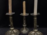 three silver candles sitting on top of a table next to each other