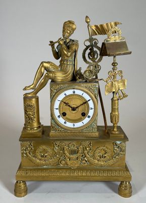 une horloge en or avec une femme assise dessus