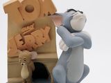 a figurine of a mouse and a mouse in front of a toy house