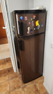 un réfrigérateur marron orné d'aimants, dans une cuisine