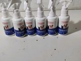 six vaporisateurs contenant des produits de toilettage pour animaux, alignés sur un comptoir