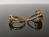 two gold rings with diamonds on a black surface