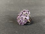 a close up of a ring with purple stones on a table