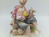 figurine en porcelaine représentant un homme assis sur un banc, tenant un oiseau dans la main