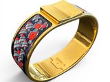 a close up of a gold bracelet with a blue and red design on it