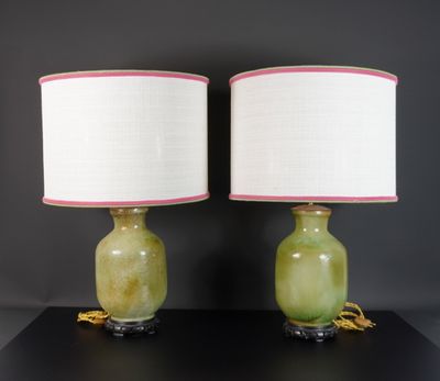 une paire de lampes vertes et roses avec des abat-jours blancs, posées sur une table noire