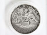 a close up of a coin on a white surface with a building in the background