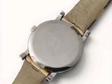 the back of a watch with a brown strap and a silver face