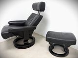 black leather reclining chair and ottoman in a corner of a room