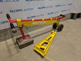 une grue rouge et jaune posée par terre à côté d'un panneau