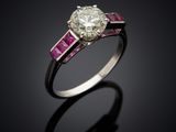 a diamond and ruby ring on a black surface