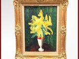 des fleurs jaunes dans un vase blanc posé sur une table, le tout dans un cadre doré