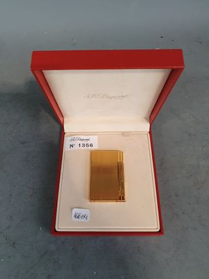 un briquet plaqué or dans une boîte rouge posée sur une table