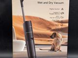 the box of a vacuum cleaner with a dog sitting on the floor