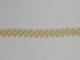 a close up of a yellow beaded bracelet on a white surface