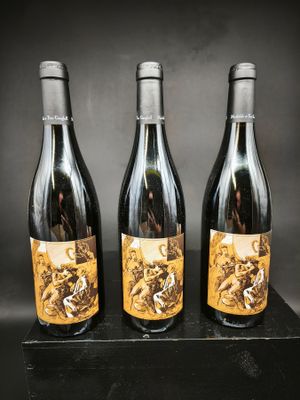 trois bouteilles de vin posées sur un bloc de bois