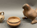 two old pottery items sitting on a gray surface next to each other