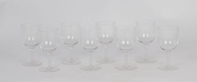 six empty wine glasses lined up in a row on a white surface