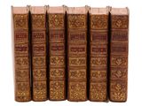 six vieux livres sont alignés sur une surface blanche