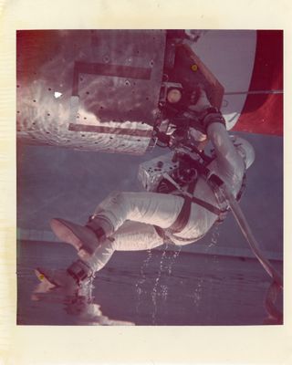 une vieille photo d'un homme en combinaison spatiale tenant un parapluie rouge