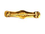 a gold brooch on a white surface with a white background
