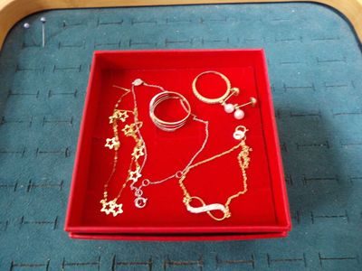 un plateau rouge sur lequel sont disposés plusieurs bijoux