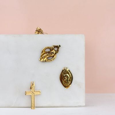 white marble clutch with gold cross, leaf, and leaf broocher