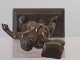a bronze statue of a woman laying on a table