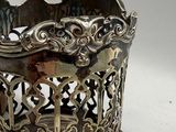 a silver vase on a wooden stand on a white surface