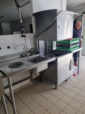 un homme debout dans une cuisine devant un évier