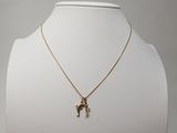 un collier plaqué or avec un pendentif en forme de cheval, porté par un mannequin