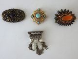three brooches and a brooch are sitting on a white surface