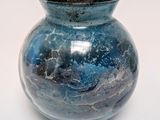 a blue vase that is sitting on a white surface