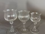 three wine glasses sitting on a table next to each other