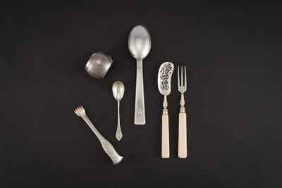 une cuillère et une fourchette en argent, ainsi qu'un repose-cuillère, posés sur une surface noire