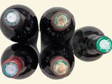 four bottles of wine are lined up in a row on a white surface
