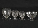 four glass goblets are lined up on a black surface
