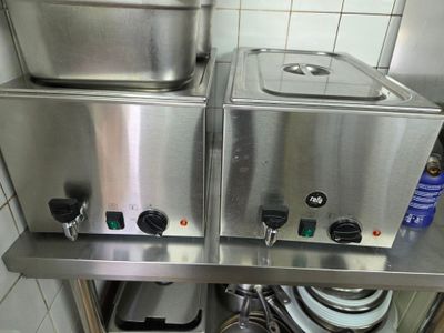 un plan de travail en acier inoxydable sur lequel sont posés deux casseroles et poêles