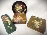 trois boîtes ornées de fleurs, posées sur une table