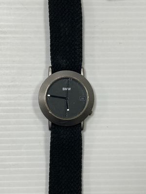une montre noire avec un bracelet noir posée sur une surface blanche