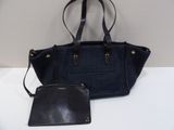 un sac à main et un portefeuille noirs et bleus posés sur une table blanche
