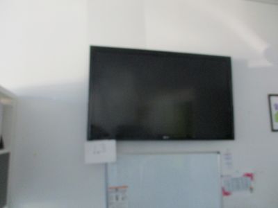 une télévision à écran plat fixée au mur au-dessus d'un réfrigérateur