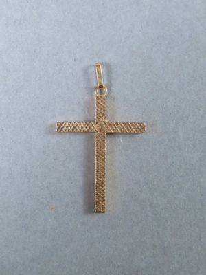 gros plan d'une croix en or sur une surface blanche