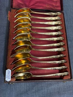 six cuillères en argent dans une boîte posée sur une table