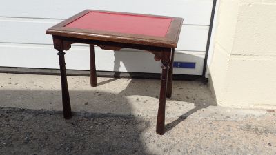 a small wooden table with a red top on the sidewalk