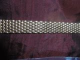 un gros plan d'un bracelet en or posé sur un tissu violet