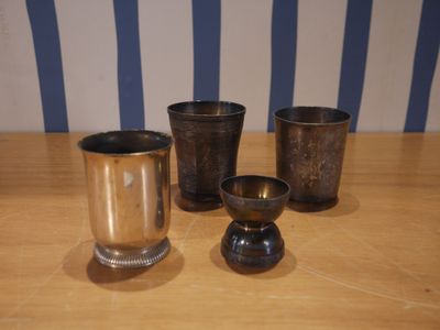 quatre tasses posées sur une table en bois, avec un mur rayé en arrière-plan