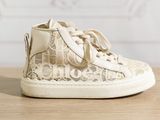 beige lace high top sneakers on a wooden surface with a white background