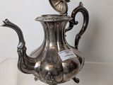 a silver tea pot on display on a glass shelf
