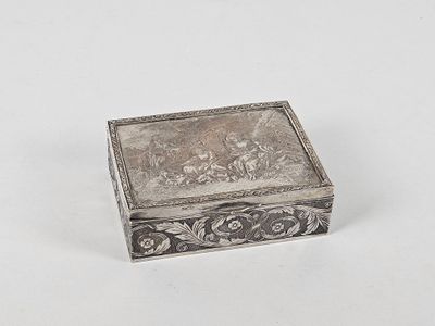 une vieille boîte en argent posée sur une surface blanche